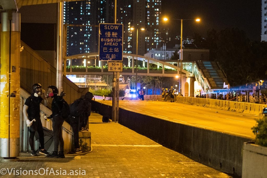 Protesters stand in cover as they contemplate how to attack the police.