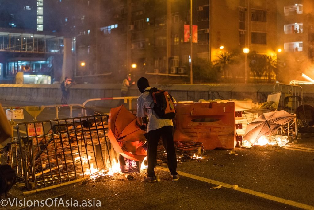 A protester feeds a blaze in Wong Tai Sin