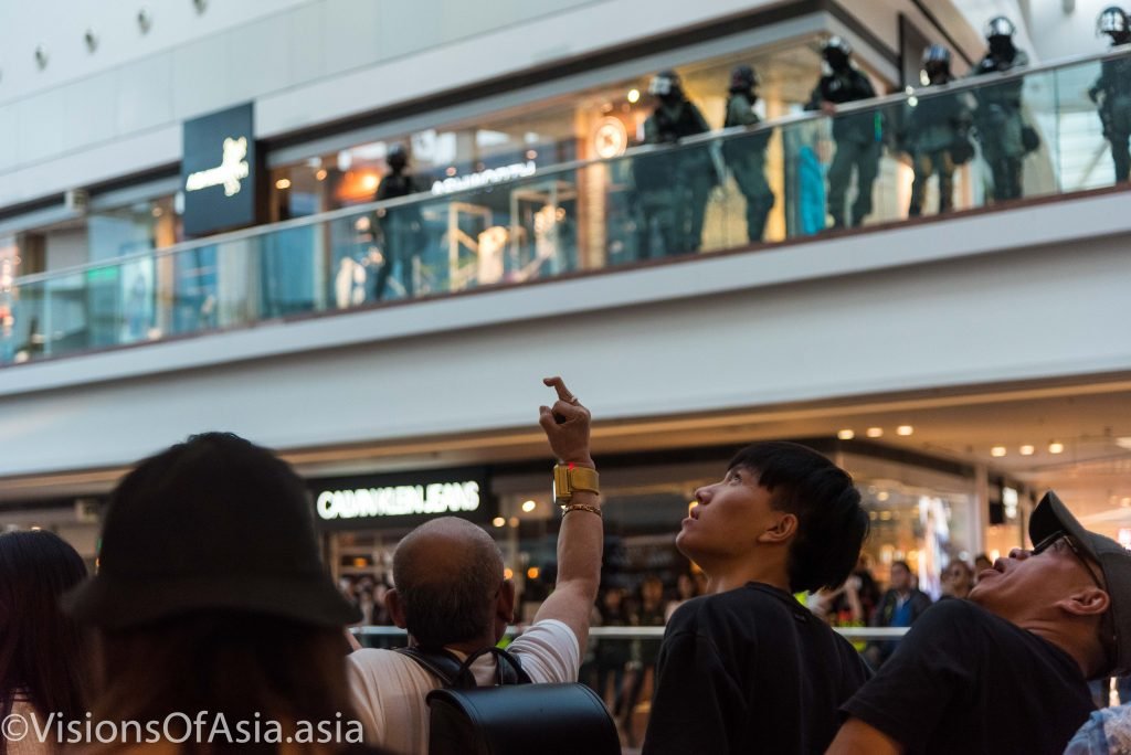 A protester gives the finger to the police