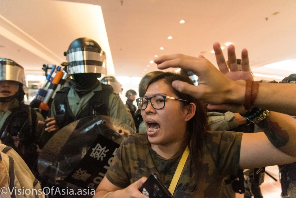 A protester is pushed ahead by riot police