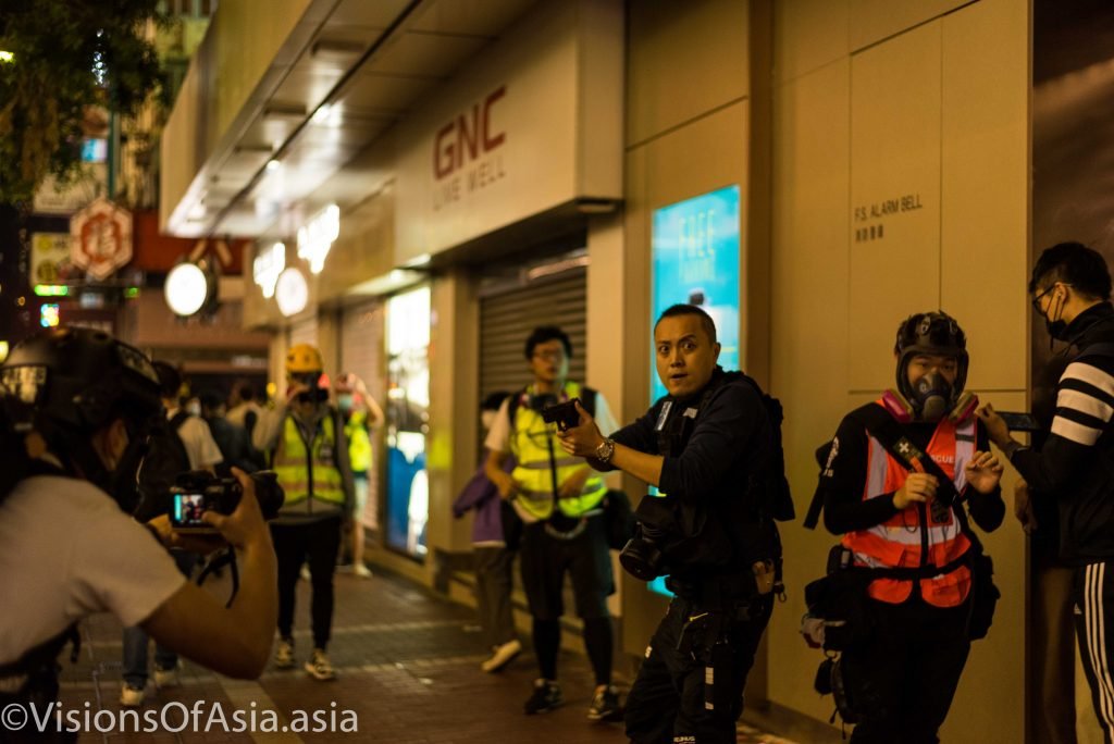 A policemen trains his gun on protesters as he flees