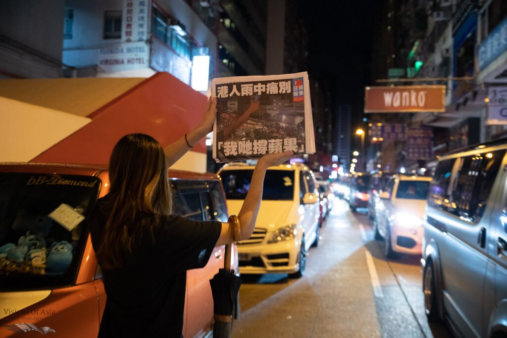 A lady exhibits the last copy of Apple Daily.