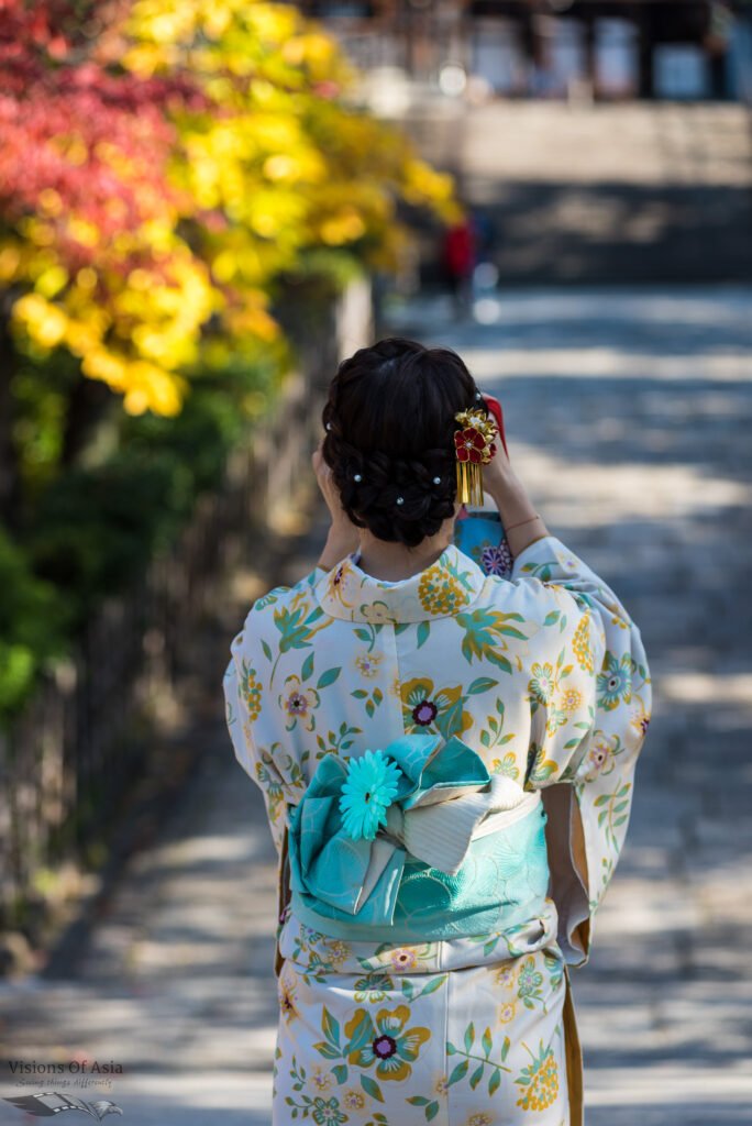 A Chinese lady in kimono takes pictures on a bridge.