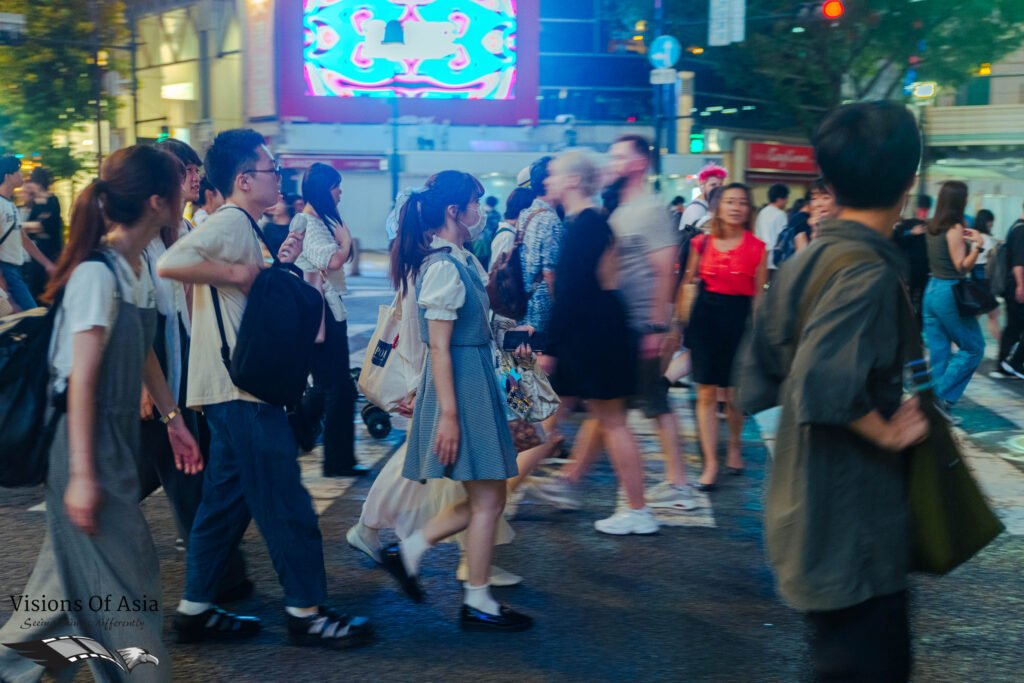 People criss-cross the Shibuya scrambled crossing at night in this panned shot.